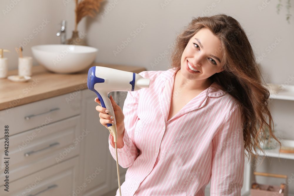 Pretty young woman with hair dryer in bathroom Pretty young woman with hair dryer in bathroom