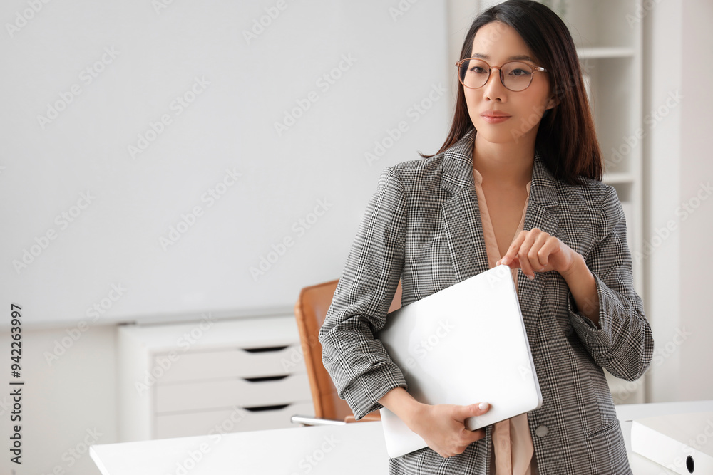 Beautiful Asian businesswoman in stylish eyeglasses with laptop in office Beautiful Asian businesswoman in stylish eyeglasses with laptop in office