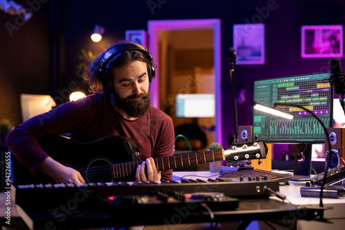 Producer composing music with his acoustic guitar in home studio, recording acoustical tunes on strings and singing melody. Audio engineer mixing and mastering his song with production gear.