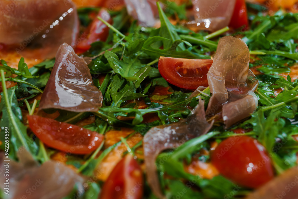 Pepperoni pizza with arugula and prosciutto. Meat pizza with cheese, cherry tomatoes and fresh arugula on a white background Pepperoni pizza with arugula and prosciutto. Meat pizza with cheese, cherry tomatoes and fresh arugula on a white background