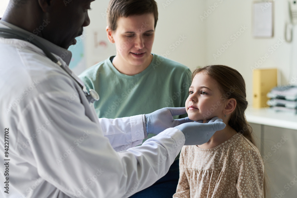 Obraz premium Doctor in white coat carefully examining young girl throat, while mother watches attentively seated beside her in a well-lit clinics