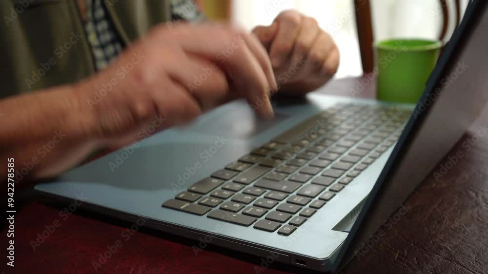 Man finishing work while drinking coffee and closing laptop on table at home.
Man finishing work while drinking coffee and closing laptop on table at home.