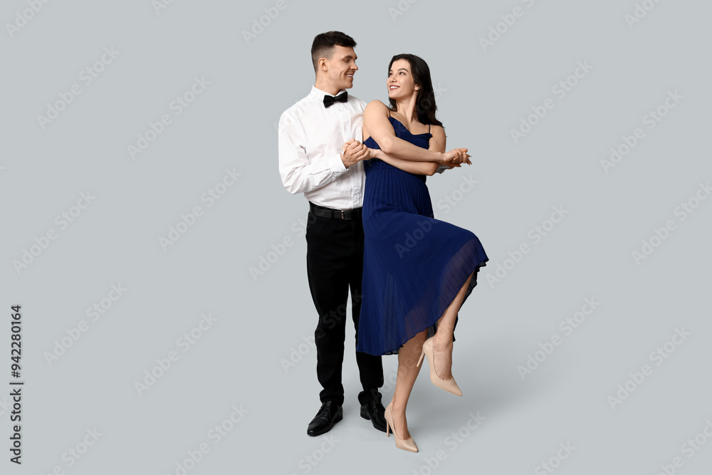 Happy young couple dancing on grey background