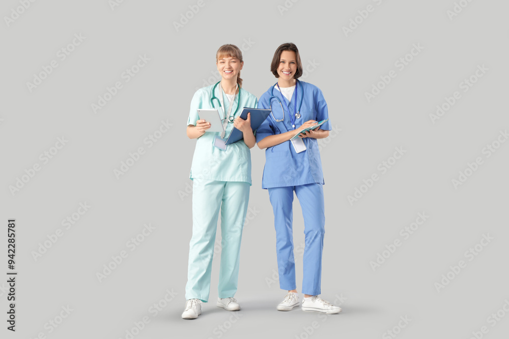 Female medical interns with notebooks and tablet computer on light background Female medical interns with notebooks and tablet computer on light background