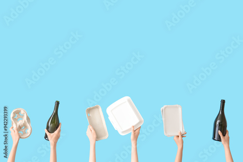 Female hands holding different garbage on blue background. Recycling concept