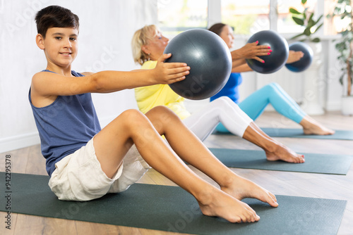 Active family three generations of mother, grandmother and teen son perform softball exercises sitting on floor, workout for beautiful figure, toned body. Bodyflex course photo