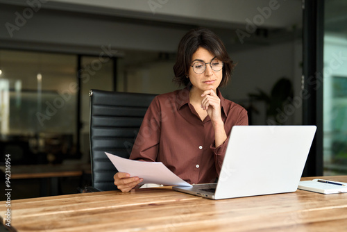 Busy serious young business woman manager working in office checking law document account invoice thinking in office. Businesswoman ceo executive or legal expert using laptop computer at work. photo