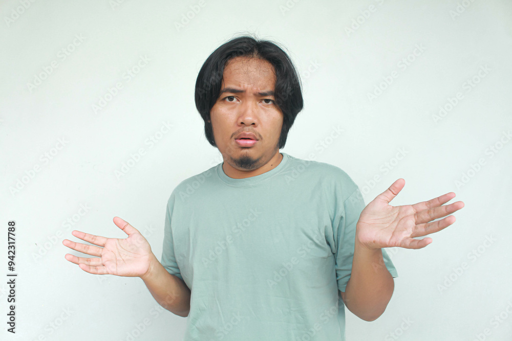 Helpless and hopeless face of log haired Asian man can not solve problem on green t-shirt. Helpless and hopeless face of log haired Asian man can not solve problem on green t-shirt.