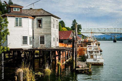 USA, Washington State. Lower Columbia River, Cathlamet Harbor, houseboats, fishing boats and homes on stilts on river shore under Puget Island Bridge. photo