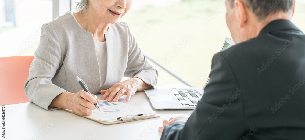 シニア男性を接客・カウンセリング・面談するアジア人シニアビジネスウーマン
