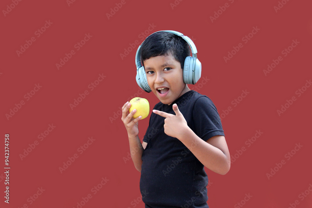 9-year-old dark-skinned Latino boy with headphones eats an apple as a sign of healthy eating while listening to music 9-year-old dark-skinned Latino boy with headphones eats an apple as a sign of healthy eating while listening to music