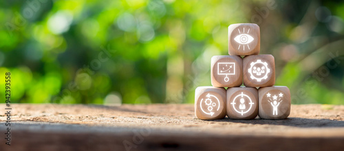 Wooden blocks with icons symbolizing advancement and innovation, stacked on a wooden surface with a blurred natural background.