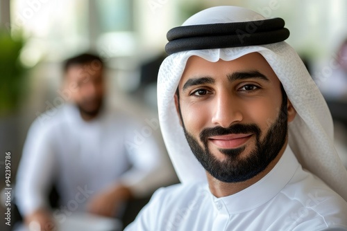 Middle East Arab man in Kandura at office with colleagues coworker workmates at background. Emirati national businessman on dishdasha ideal for Middle Eastern diversity concept with generative ai