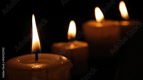 Multiple candles burning in the dark