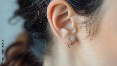 A close-up of an ear adorned with a small hoop earring. photo