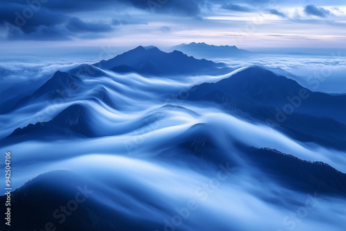 A serene, high-altitude landscape where a range of mountains appear to float above a dense sea of clouds, with the scene bathed in the cool, blue light of early morning. 