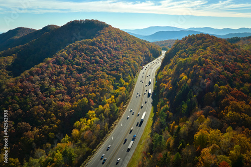 View from above of I-40 freeway in North Carolina heading to Asheville through Appalachian mountains in golden fall season with fast driving trucks and cars. Interstate transportation concept