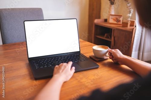Mockup image of a woman working on laptop computer with blank white desktop screen while drinking coffee