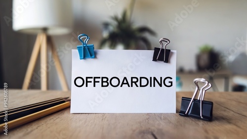 A white note with the text Offboarding. The note is placed on a wooden surface