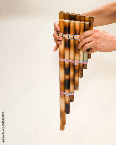 Male hands holding a rondador on a beige isolated background. Andean instrument, pan flute, traditional South American instrument.
