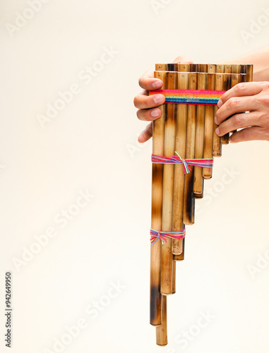 Male hands holding a rondador on a beige isolated background. Andean instrument, pan flute, traditional South American instrument.