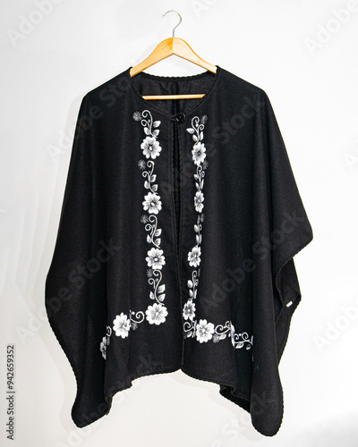 Hand embroidered sheep wool poncho, colorful, flower embroidery, black poncho on white background, no people, Ecuadorian poncho, Andean, handicraft.