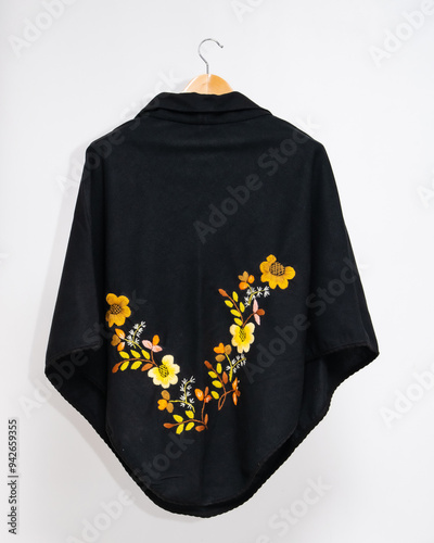 Hand embroidered sheep wool poncho, colorful, flower embroidery, black poncho on white background, no people, Ecuadorian poncho, Andean, handicraft.