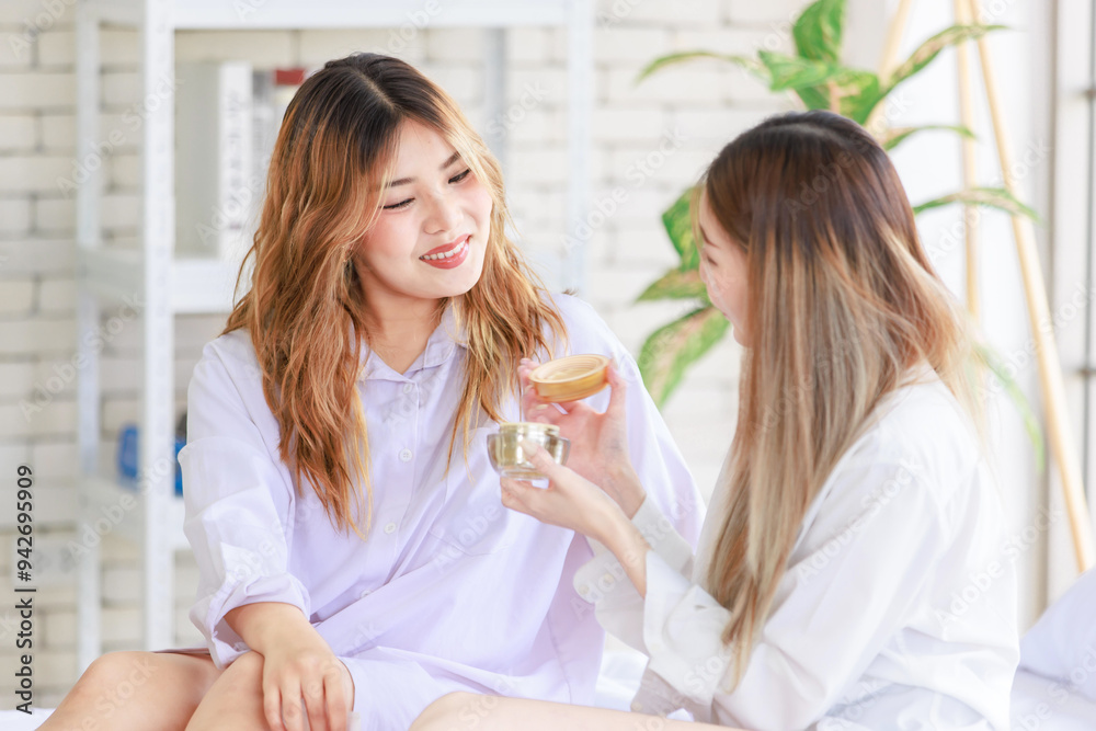 Two happy beautiful Asian female girlfriends with cosmetics make face take care of skin, Attractive women trying beauty products relax on a white bed, Concept teenage or friends lifestyle at home. Two happy beautiful Asian female girlfriends with cosmetics make face take care of skin, Attractive women trying beauty products relax on a white bed, Concept teenage or friends lifestyle at home.