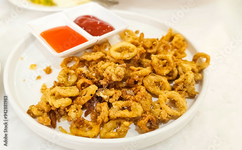 Crispy breaded squid rings. Deep-fried crispy squid with sweet sauce on in plate on table. Crunchy Fried squid appetizer, served with beer.