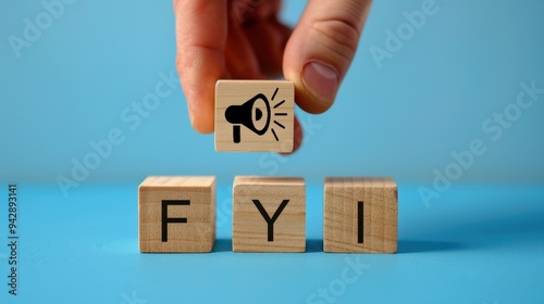 Hand put the speaker on FYI wooden block character on blue background. Information announcement concept.