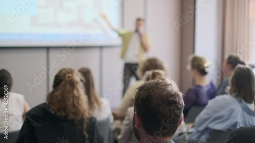 Group of people engaged in a presentation, focusing on the speaker delivering information in a conference setting.
