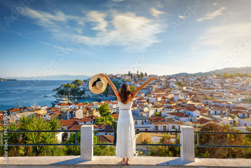 Obraz na płótnie A happy tourist woman enjoys the beautiful summer sunset view of the town of Skiathos island, Sporades, Greece w salonie