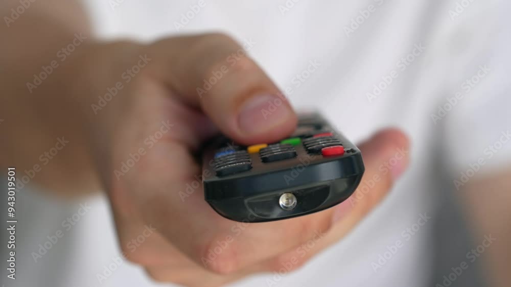 TV remote control.
A man watches TV.
A man's hand holds the TV remote control.
Buttons on the remote control.
TV, transmission, watch, buttons