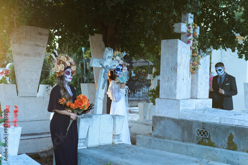 Group of three people made up as catrines in a cemetery. Day of the dead celebration. photo