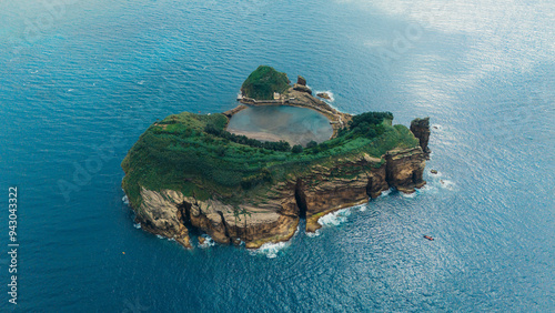 Aerial view of a lush green islet with a historic building in the Azores