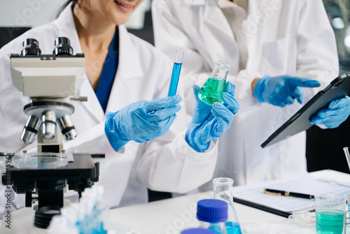 Young scientists conducting research investigations in a medical laboratory, a researcher in the foreground is using a microscope photo