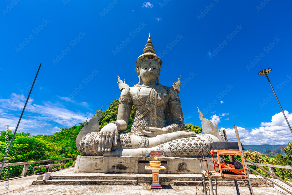 Background of a religious tourist attraction in Phitsanulok, Thailand, Wat Pa Rang Mi Wanaram, with a large Buddha statue on a mountain, overlooking the surrounding green rice fields. Background of a religious tourist attraction in Phitsanulok, Thailand, Wat Pa Rang Mi Wanaram, with a large Buddha statue on a mountain, overlooking the surrounding green rice fields.