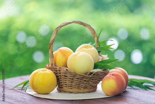 Fresh three kinds of peaches on blurred greenery background, Three colored peaches in basket on wooden table in garden. photo