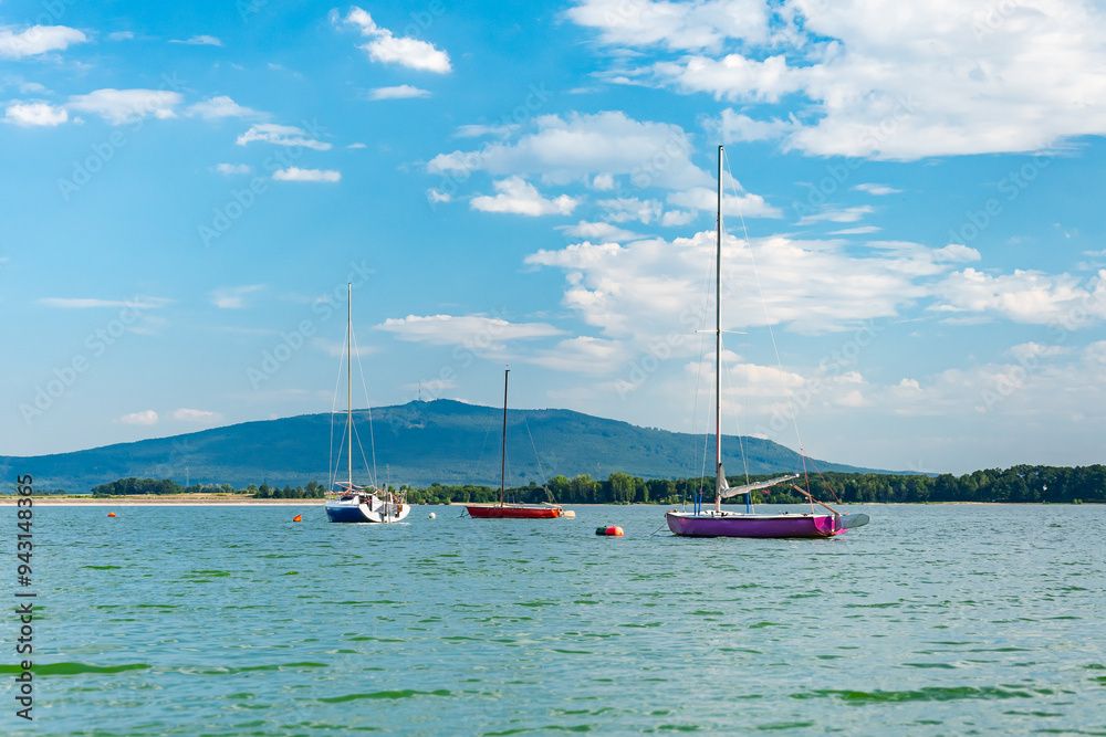 Fototapeta premium Zalew Mietkowski, mountain landscape with a view of Mount Sobotka, sailboats moored at the shore. A popular place for summer recreation and water sports.