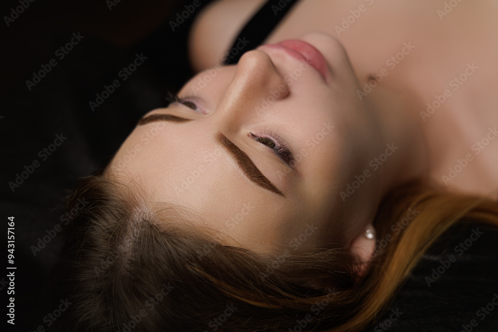 Beautiful eyebrows after permanent eyebrow makeup girl lying dark cosmetology salon Permanent eyebrow makeup, eyebrow tattooing with brown pigment for PMU. Beautiful eyebrows after permanent eyebrow makeup girl lying dark cosmetology salon Permanent eyebrow makeup, eyebrow tattooing with brown pigment for PMU.