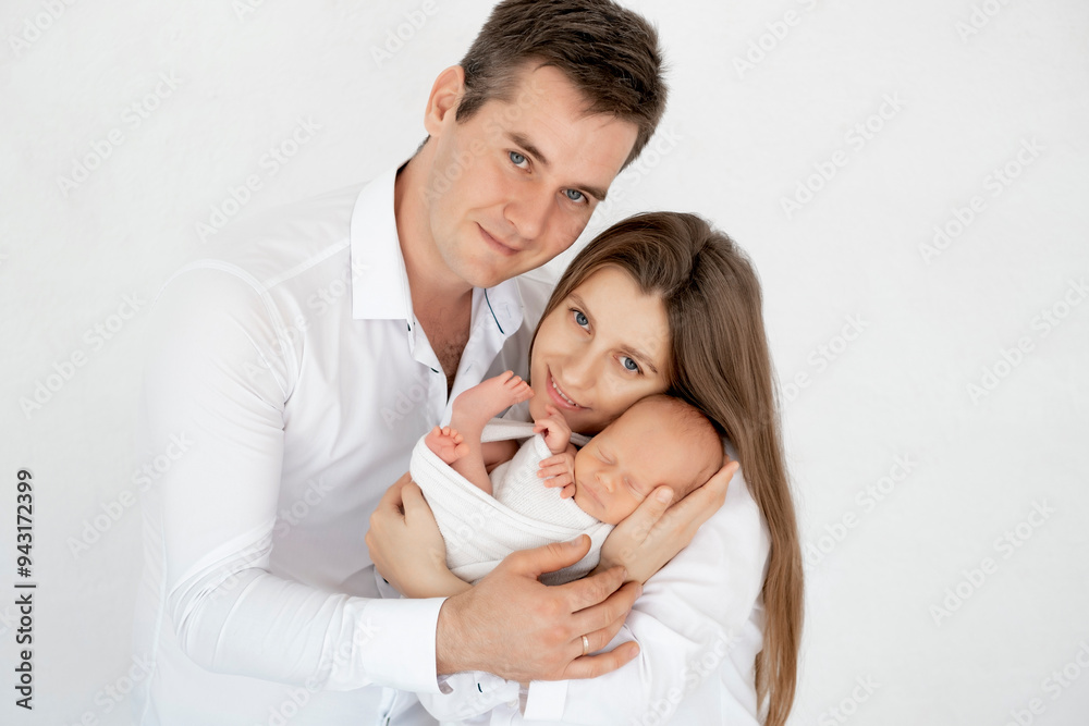 young parents with a newborn baby hug and kiss, happy mom and dad admiring the baby at home on the bed, a happy family caring for a small child, a place for text young parents with a newborn baby hug and kiss, happy mom and dad admiring the baby at home on the bed, a happy family caring for a small child, a place for text