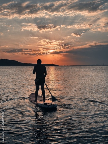 Man on a sap board in a sunset. Sup board at sunset photo