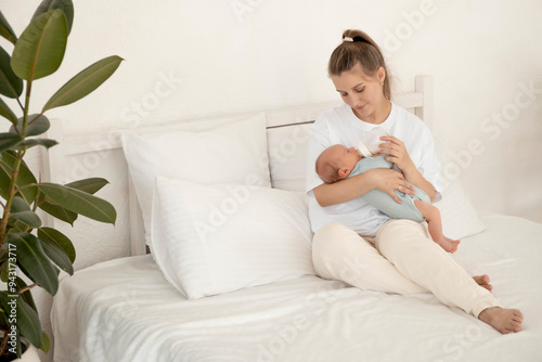 feeding a baby from a bottle, a mother feeds a newborn baby with milk while holding it in her arms, baby food, a baby sucks a bottle