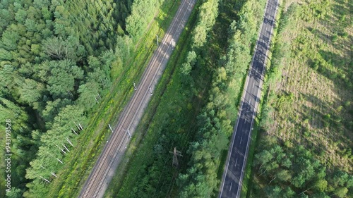 Railway and highway passing through forest captured from the sky photo