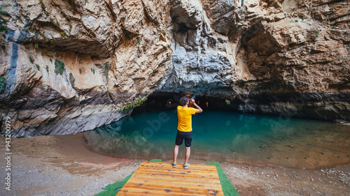 A tourist photographing the beauty of Altinbesik Cave. The tourist takes photos of the surroundings with his camera in hand. Antalya, Turkey. photo