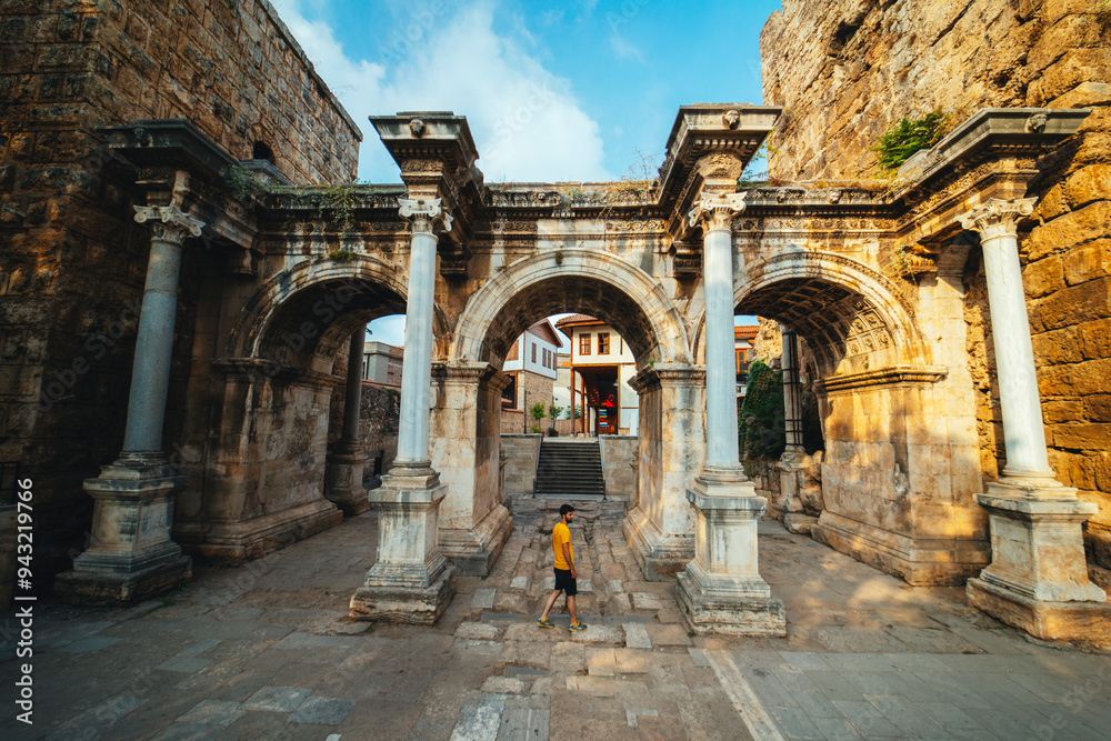 Obraz premium Hadrian's Gate. Young tourist in yellow t-shirt examines the gates. Photo taken on a cloudy day. Turkey.