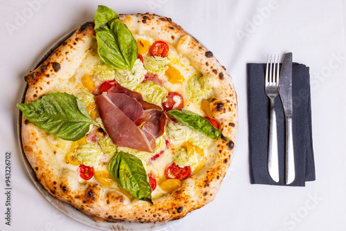 Pizza tradizionale napoletana con prosciutto crudo, pomodori rossi, pomodori gialli, ricotta e basilico fresco servita in una pizzeria elegante photo