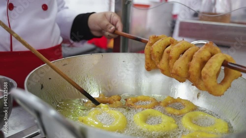 A woman is cooking picarones in a pan. Peruvian food