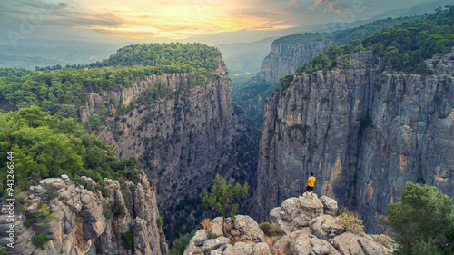 A man climbing Tazi Canyon and watching the view. The sun is added to the magnificent harmony of trees and mountains in the canyon. photo