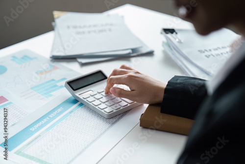 Business Accountant Working on Financial Reports with Calculator and Documents in Modern Office Setting